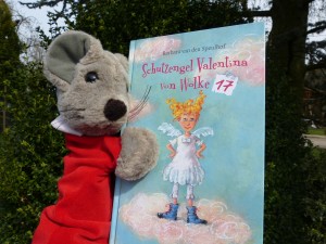 Die Maus Mimi hält das Buch in der Hand.